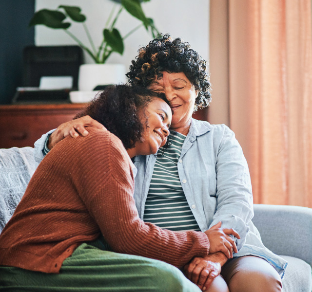 Two people on a couch hugging.