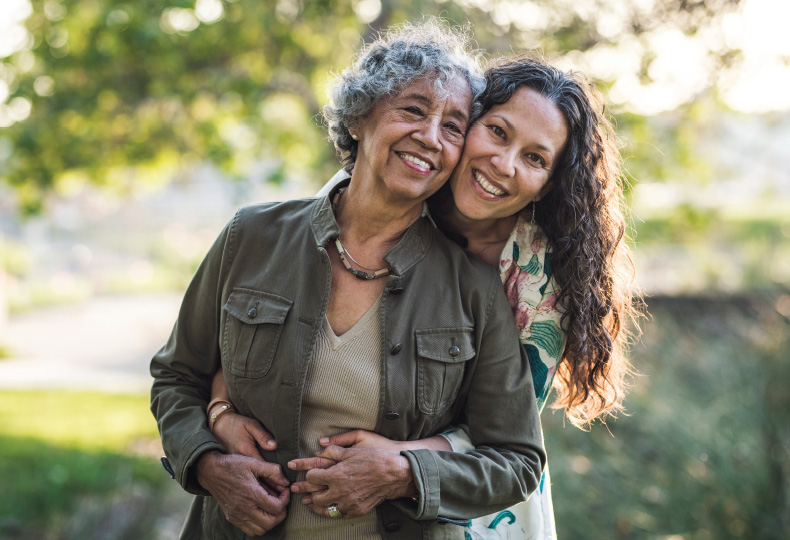 Two people outside, hugging and smiling.