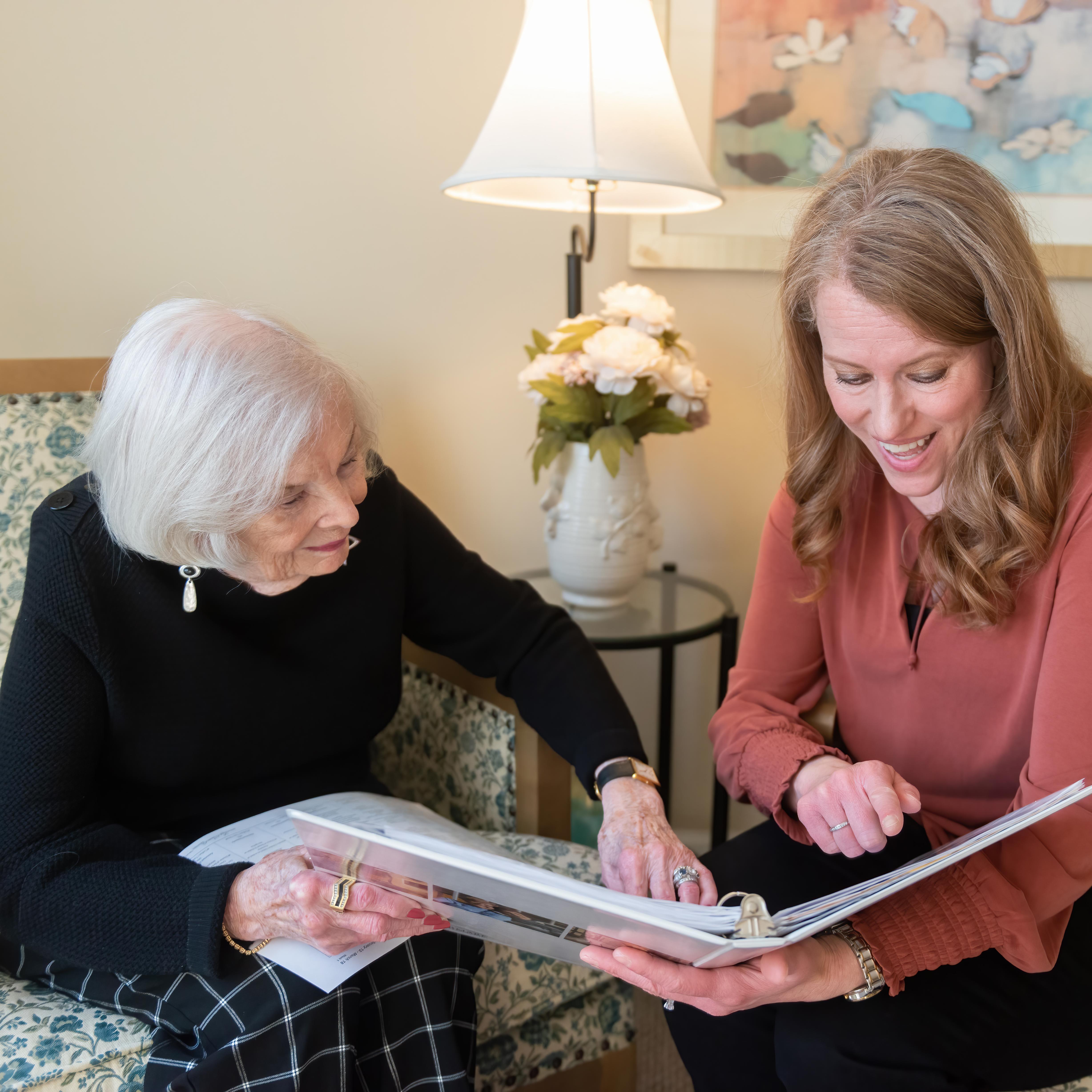 Two people looking at an album while sitting on a couch.