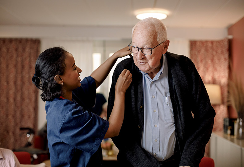 A resident is walking alongside a caregiver.