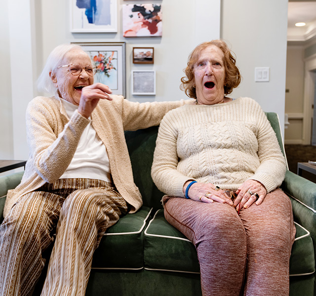 Two friends on the couch making funny faces.