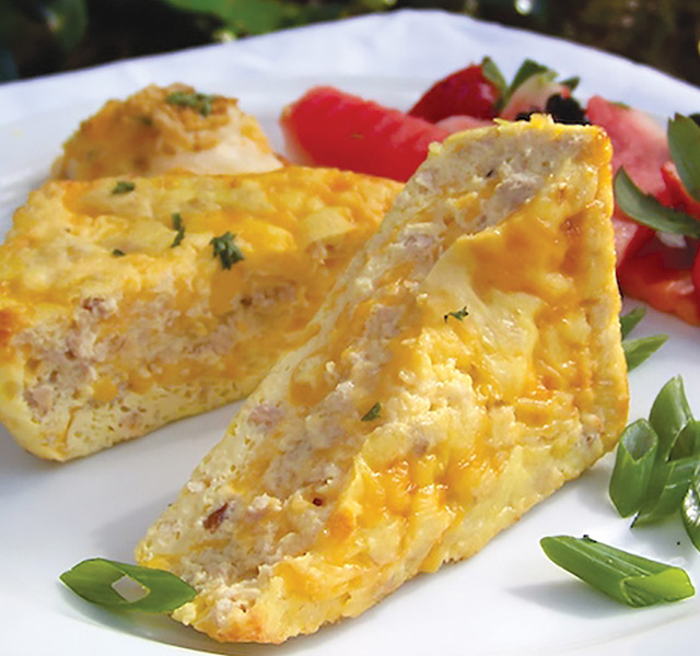 Two pieces of quiche with red fruit on a plate.