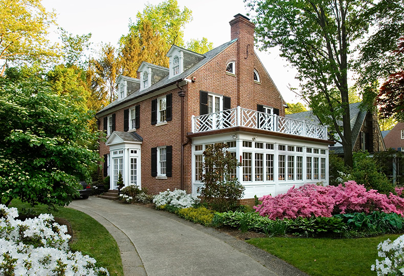 An old colonial style brick house surrounded by a garden.