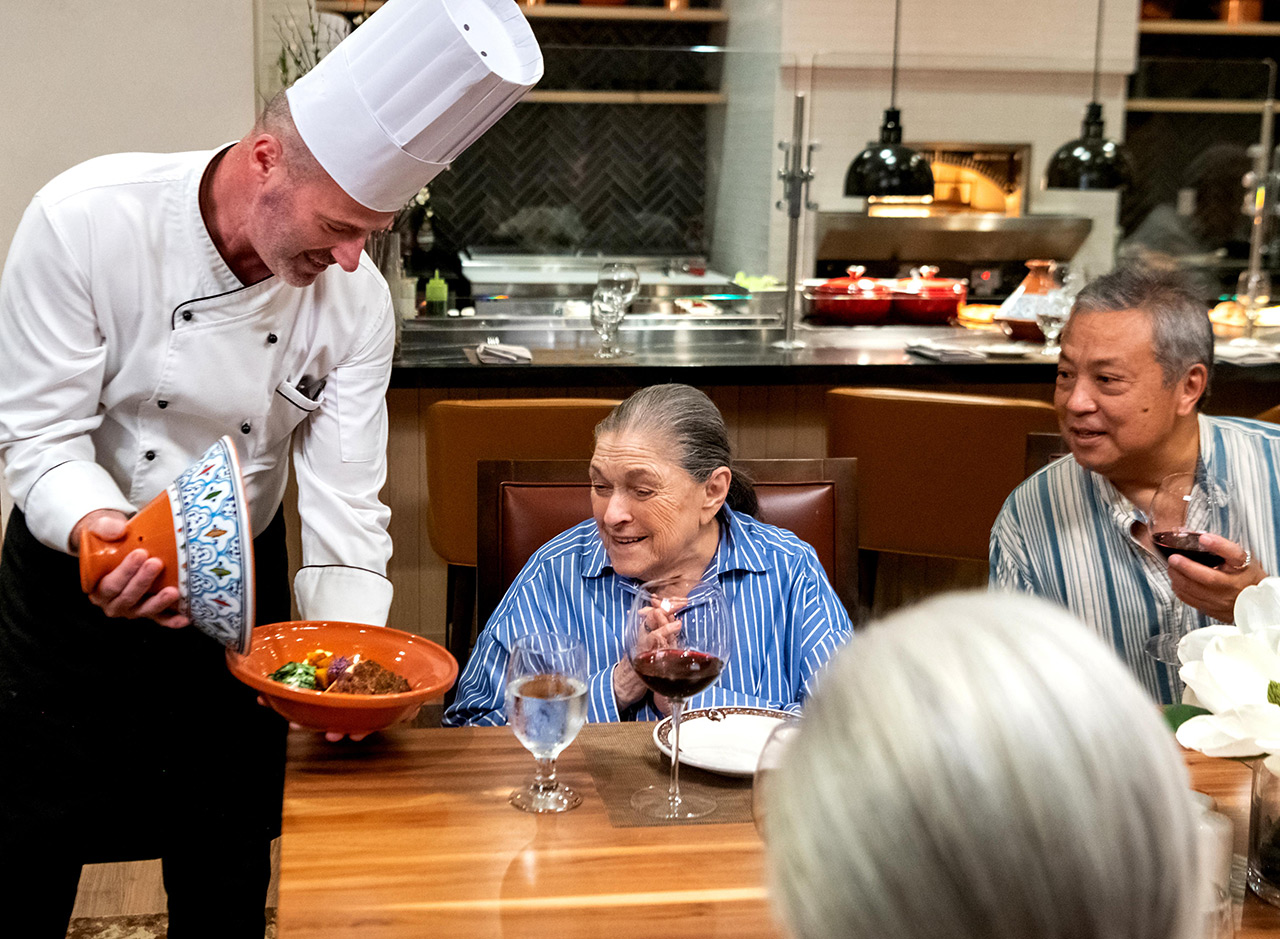 Chef greets table with a group of people.