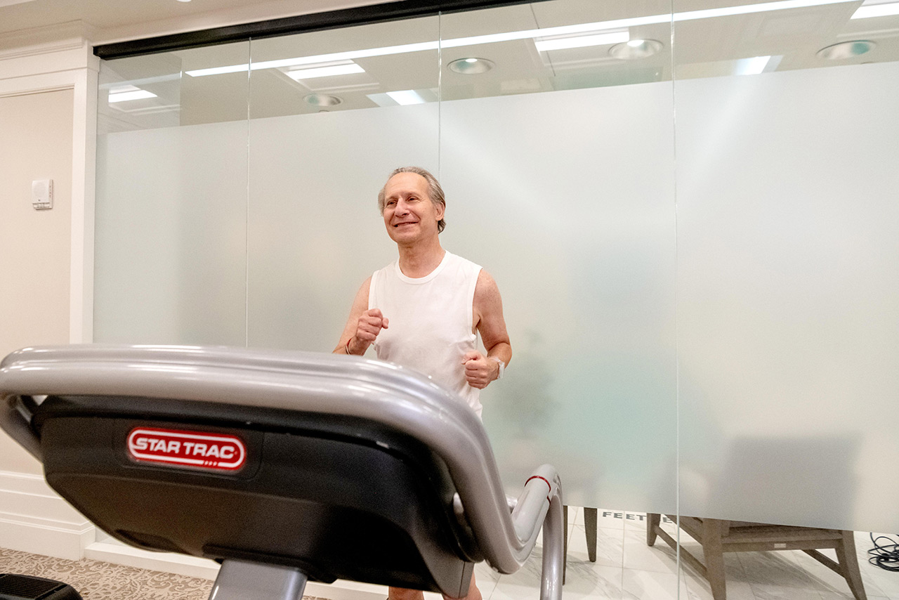 Resident on treadmill in fitness room.