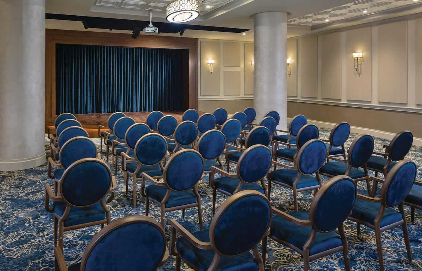 The performance centre at The Watermark at Brooklyn Heights. featuring blue velvet backed chairs and blue velvet curtains adorning a mahogany stage