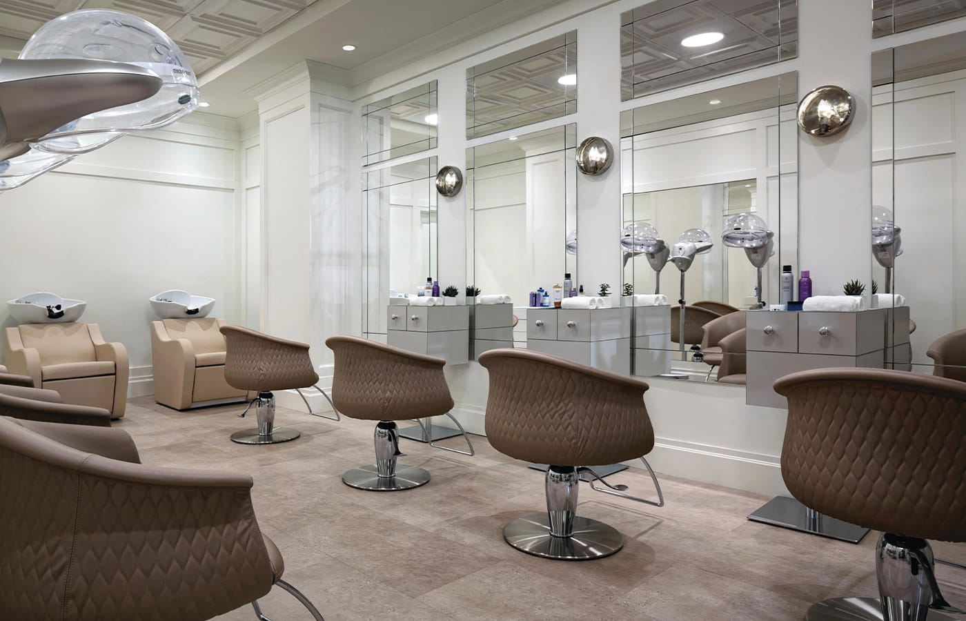 A row of hair salon chairs and blow dryers within Indulge at The Watermark at Brooklyn Heights.