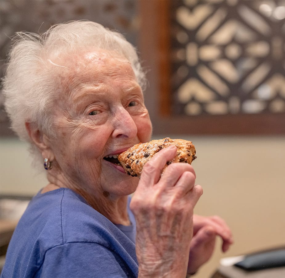 Happy resident eating a scone.