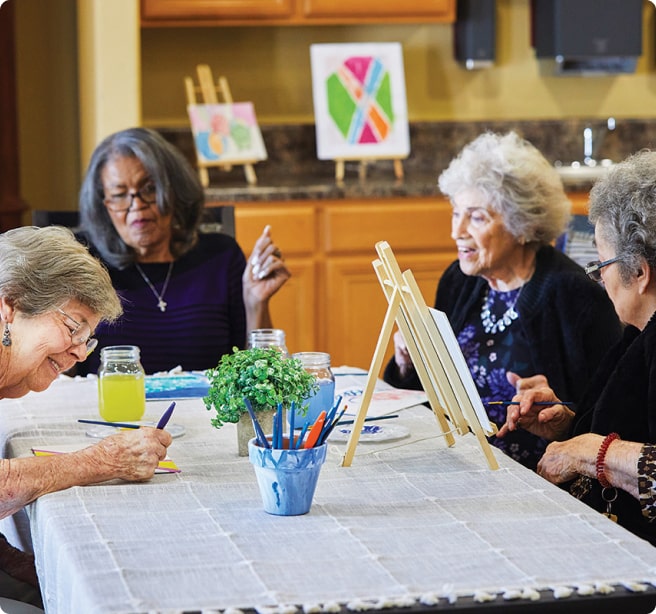 Residents sitting at a table painting.