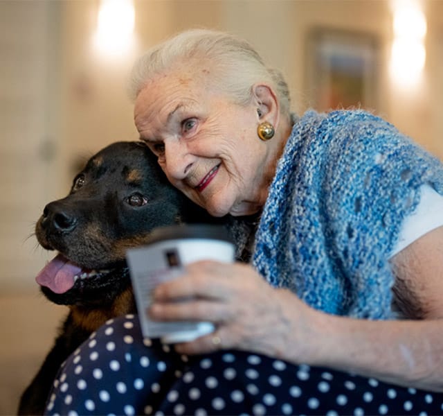 A resident hugging a black lab