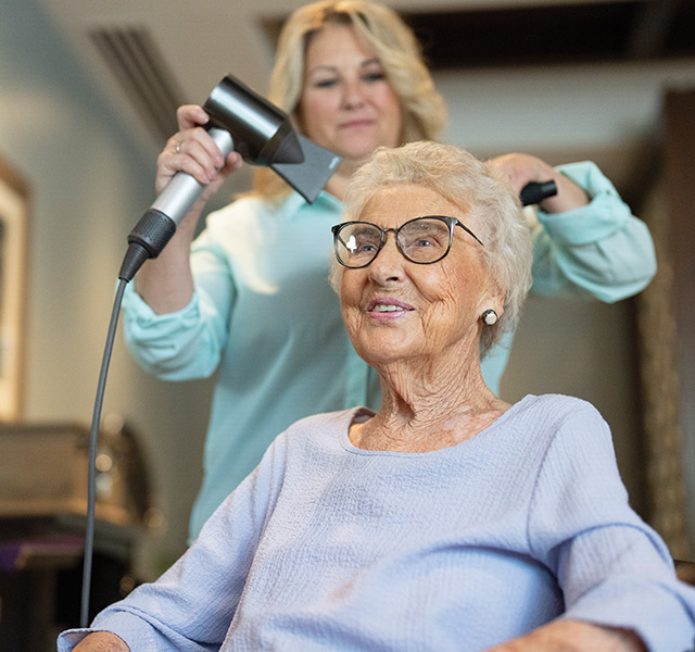 Hairdresser cutting resident's hair.