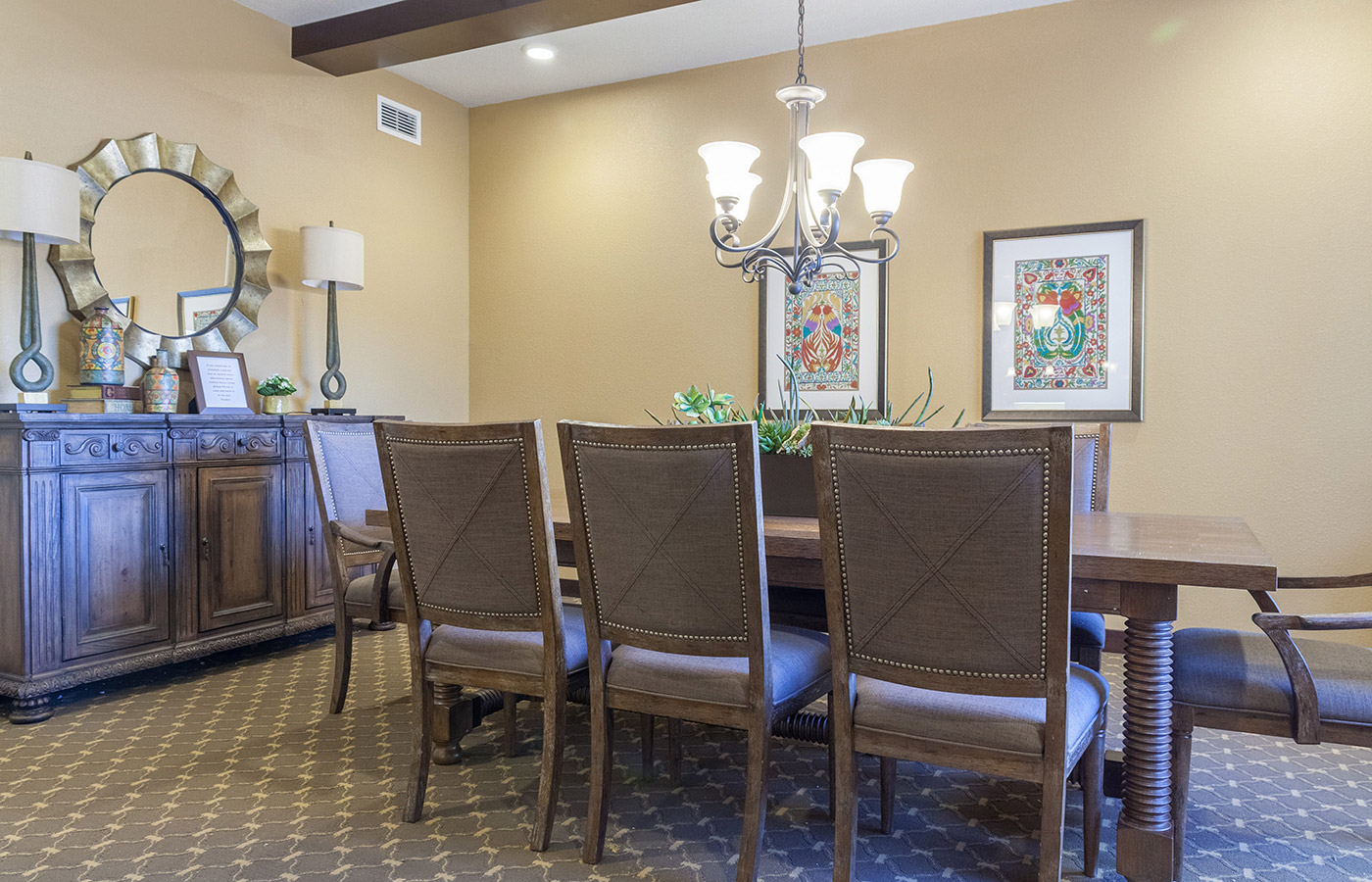 An eight place dining table with two picture frames on the adjacent wall.