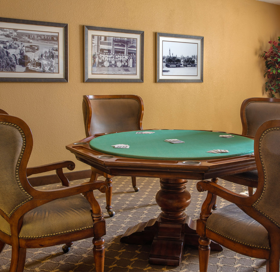 A poker table with multiple paintings on the wall behind.