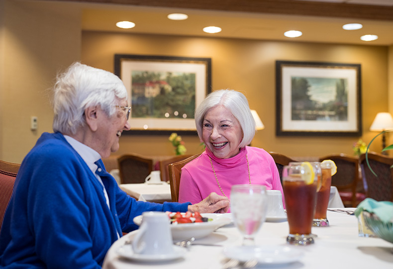 Two residents chatting and enjoying a meal together.