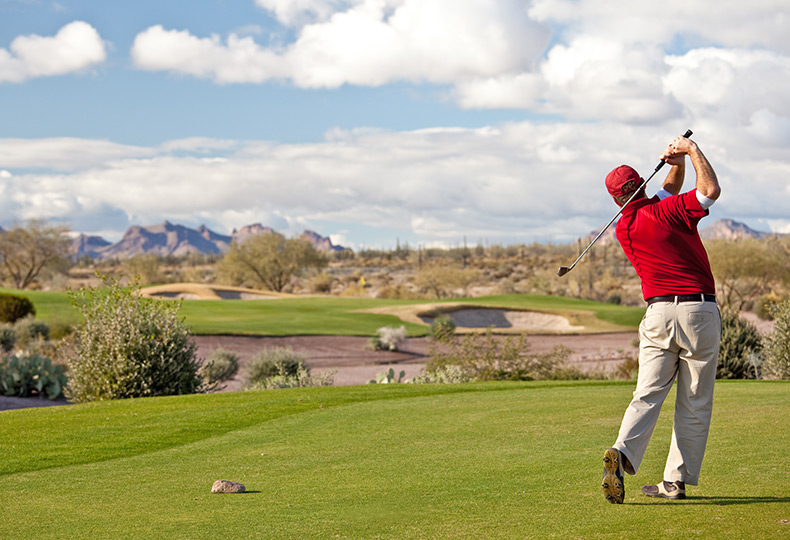 A person is playing golf in desert golf course.