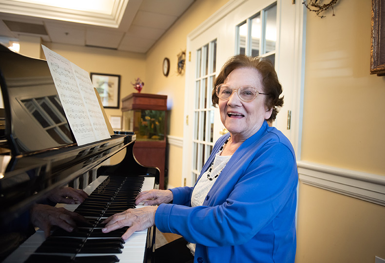 Resident is playing the piano and smiling.