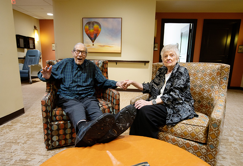 Two residents sitting in chairs in the common area.