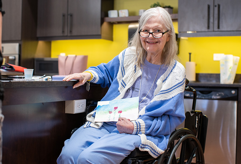 A resident smiling and holding a book.