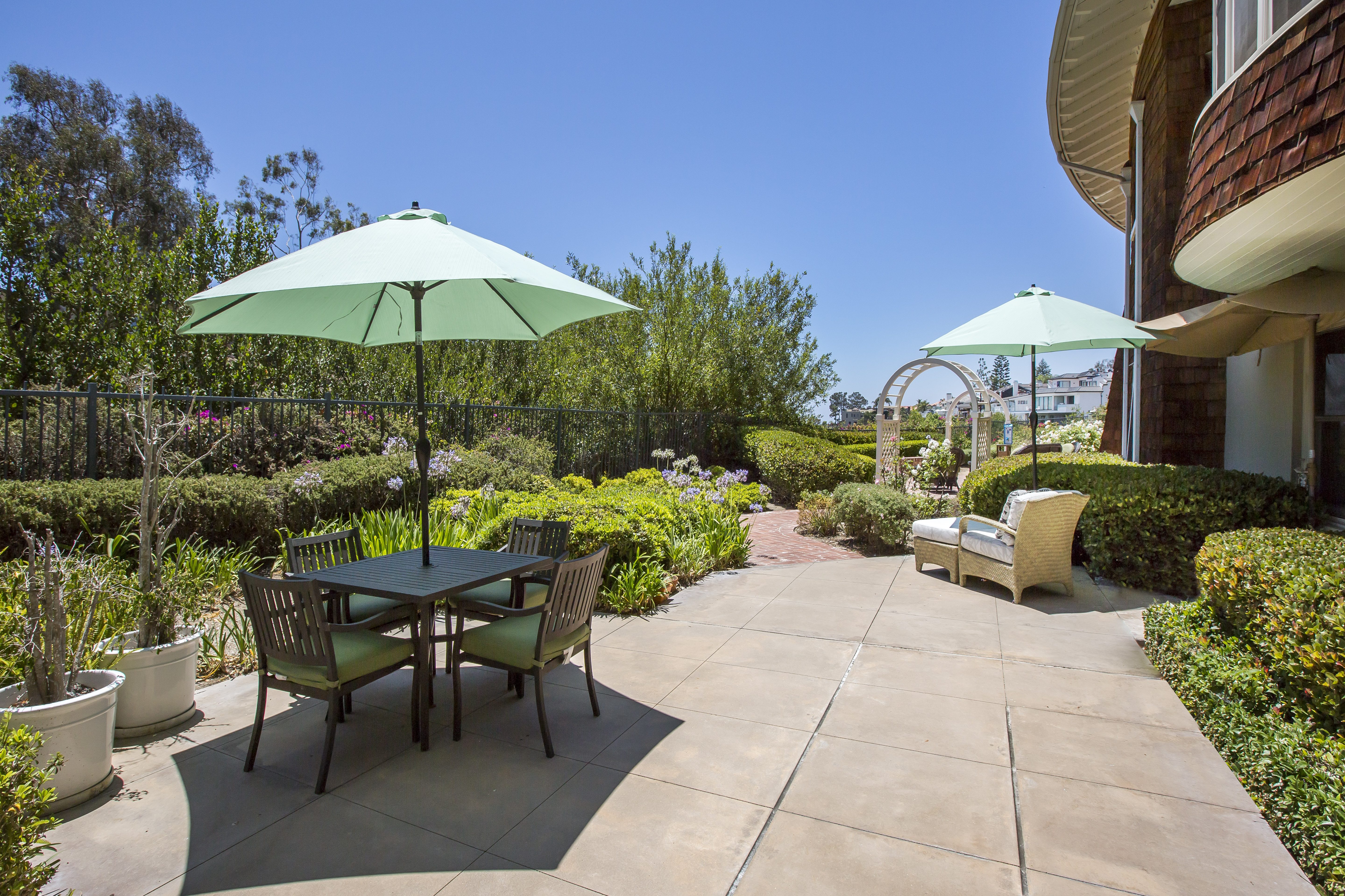 outdoor patio with tables, chairs and umbrellas in garden area