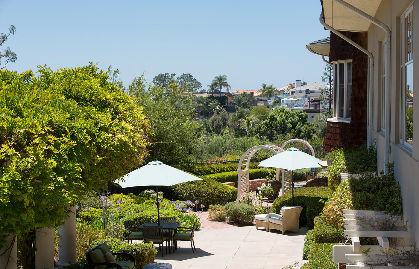 Patio and garden with tables, chairs and umbrellas.