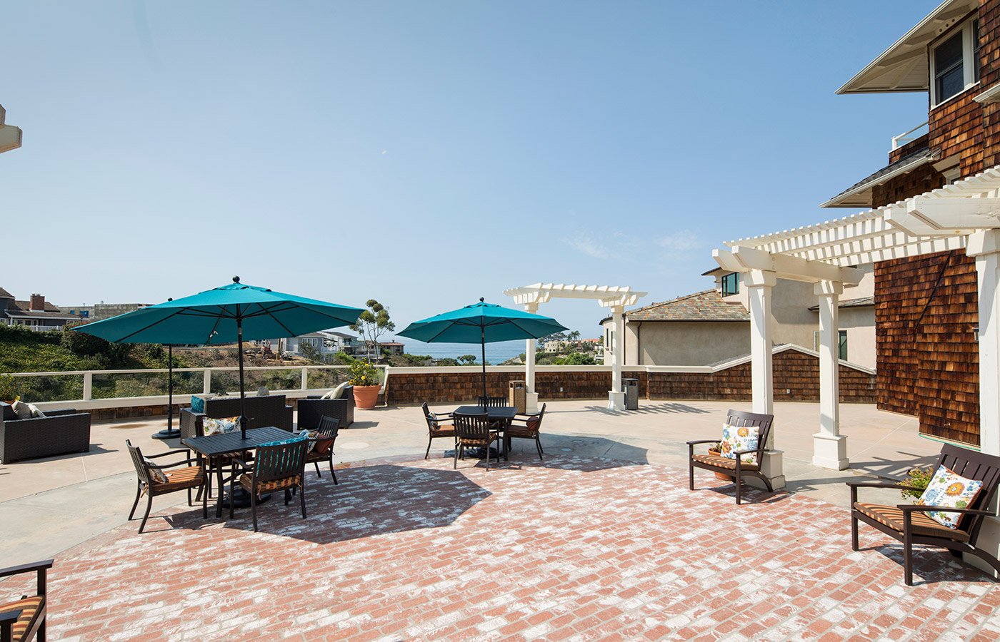 large sunny patio area with table, chairs and umbrellas