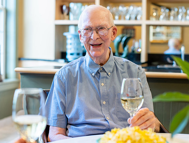 A resident is sitting at a table with a glass of wine and popcorn.