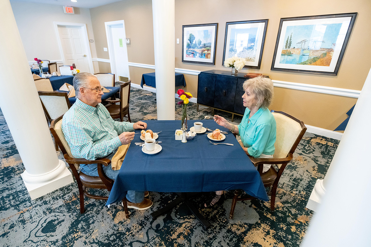 Two residents are eating in the dining area at East Village Place.