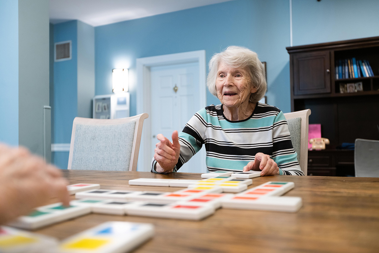 A resident is playing a game at a table in the activity room.