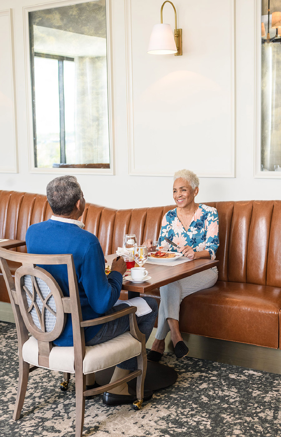 Two residents are sitting at a table in a restaurant enjoying a meal together.