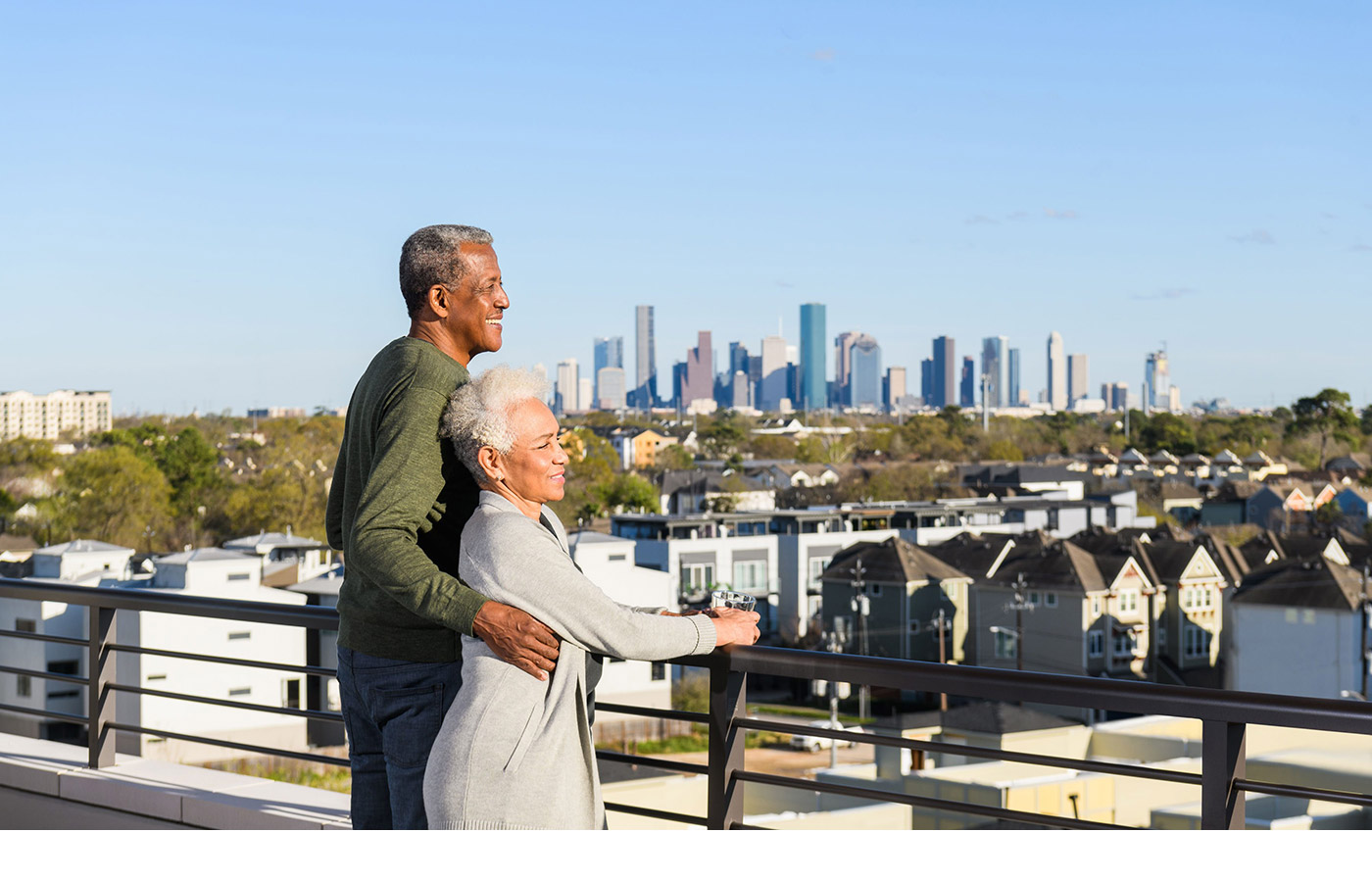 Two residents are on a rooftop deck overlooking the view of the city.