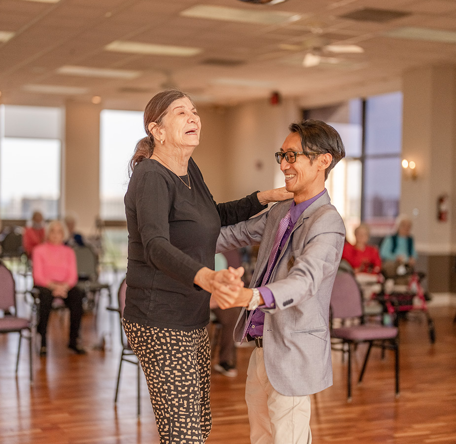 A resident is dancing with an instructor in a class.