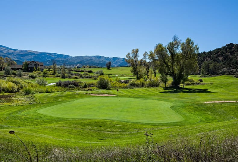A golf course with surrounding mountains.