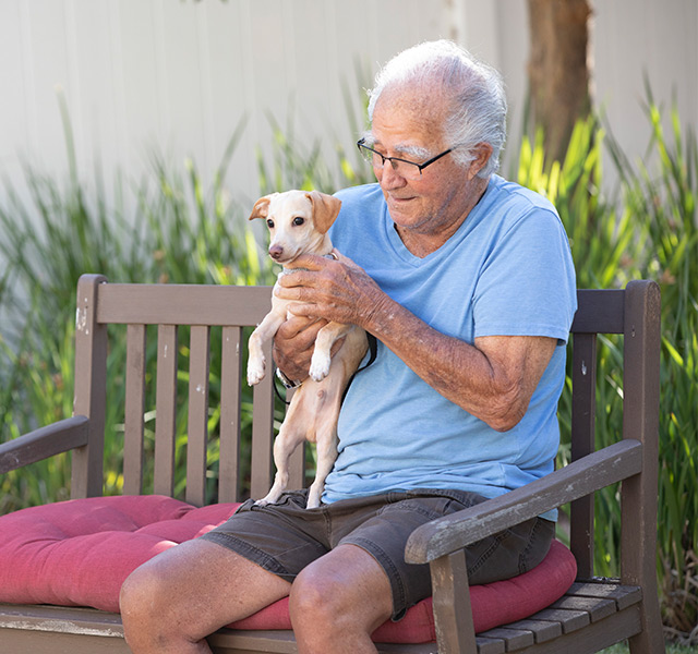 A person holding their pet, sitting on a bench.