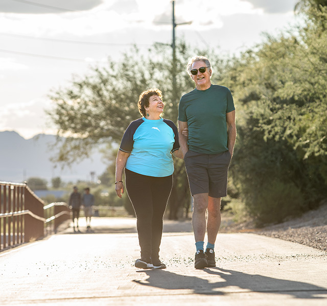 Two people are walking on path outside.