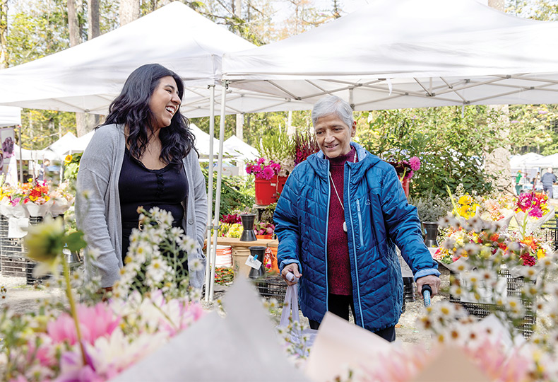 Two people looking at flowers at a farmers market.