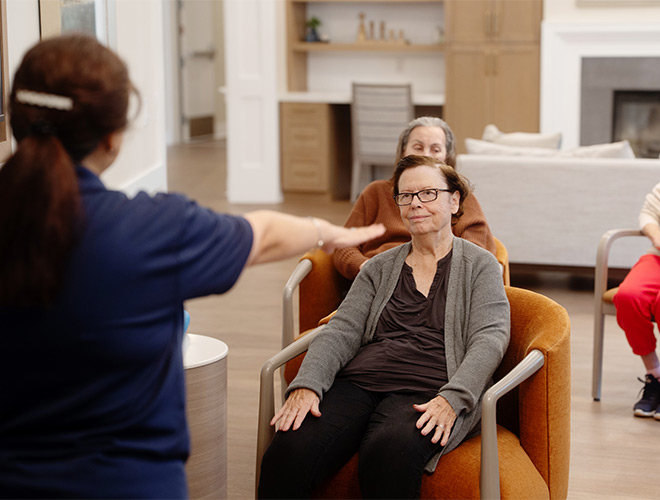 A person teaching a seated fitness class.