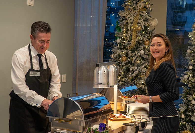 A person and chef by the buffet table.