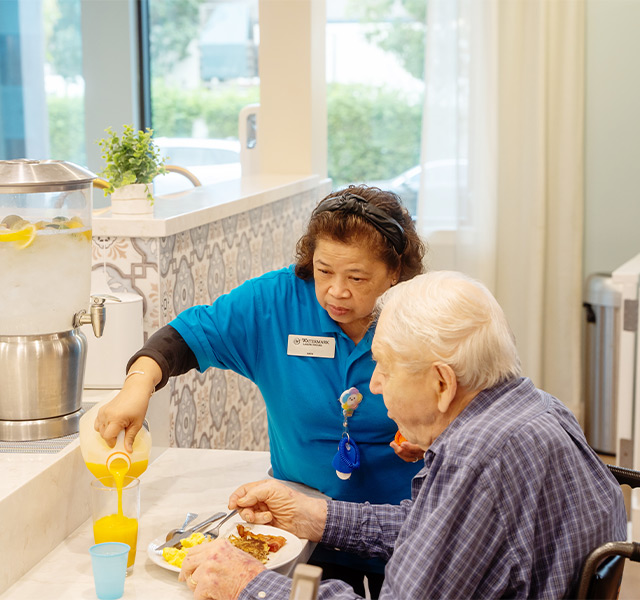 A person pouring orange juice for another.