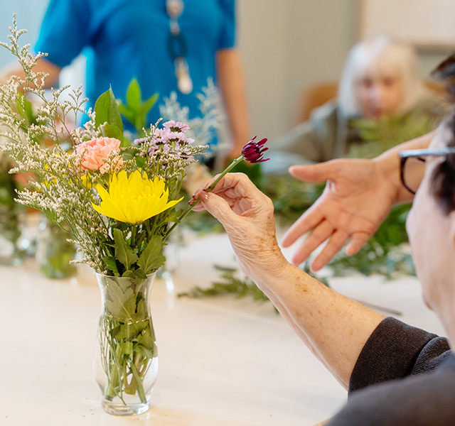 A person putting a flower in a vase.