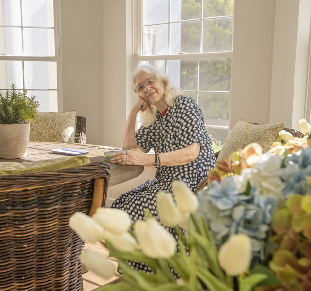 A resident sitting at a table near a large bouquet of flowers.