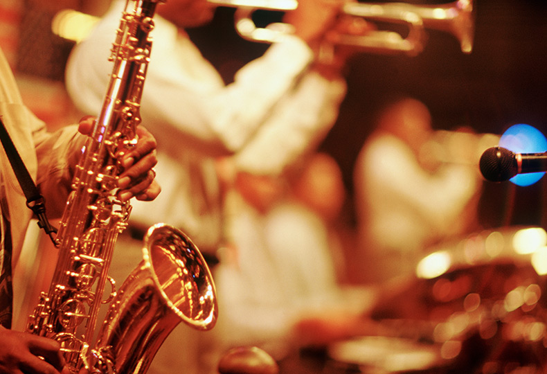 Close up of someone playing a saxophone in a band.