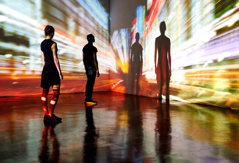 People standing in an interactive light display at a museum.