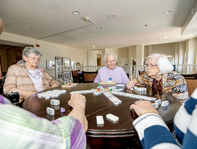 a group of residents sitting around a table playing dominoes