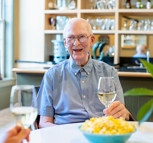 Residents sitting at a table with a glass of wine and a bowl of popcorn