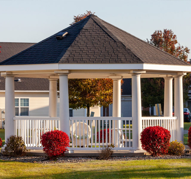 Gazebo surrounded by bushes and flowers.