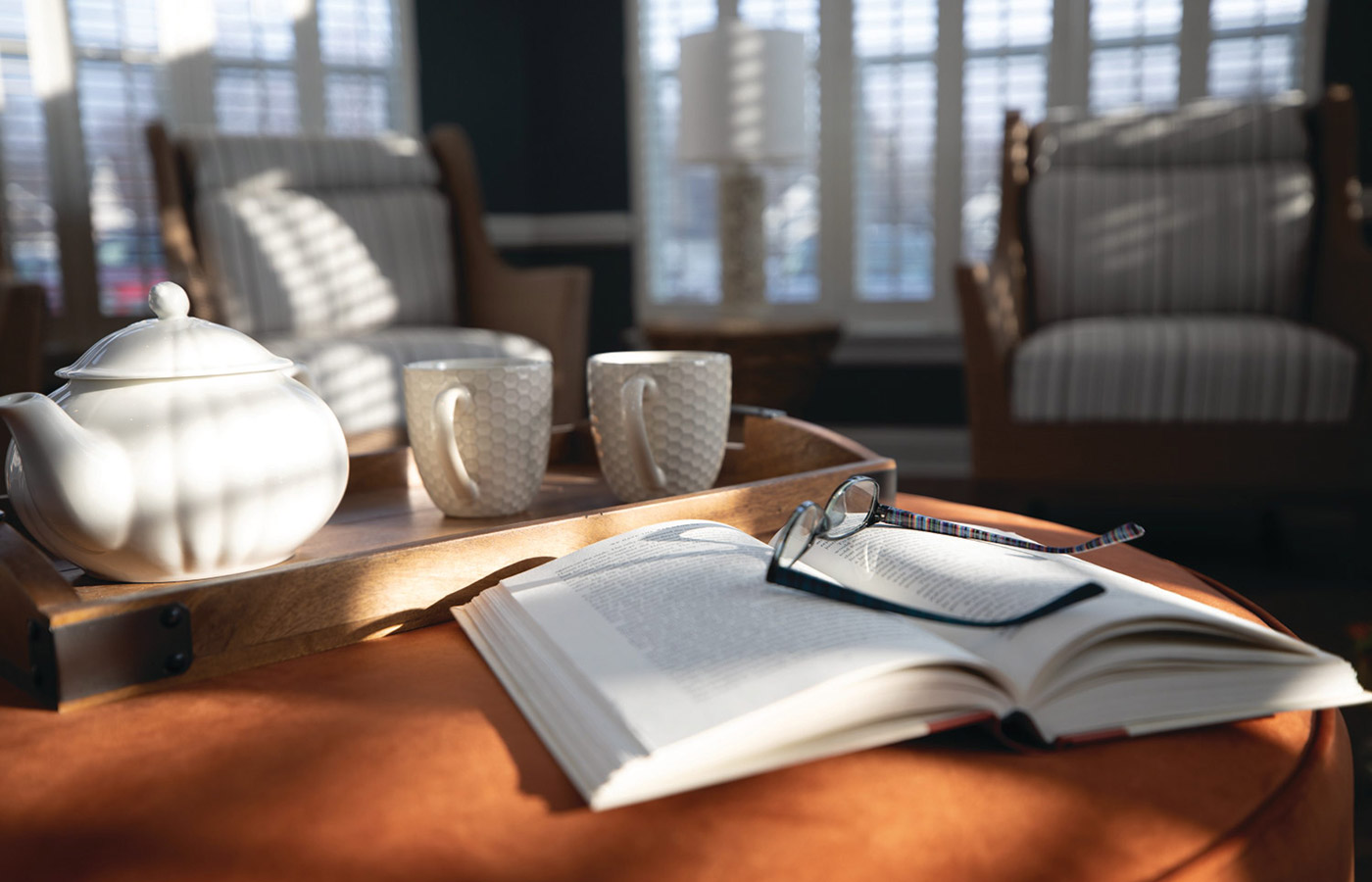 Pot and tea and book with glasses on tray.