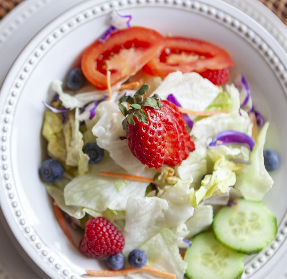 Salad of greens and a strawberry.