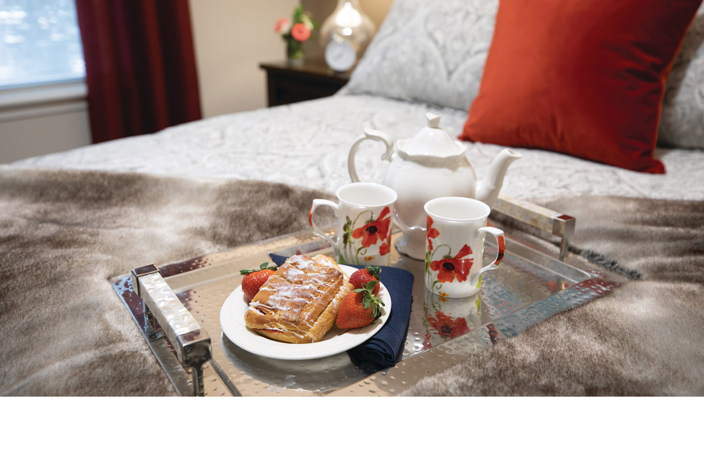 A tray of breakfast and coffee on a bed in an apartment at The Legacy at Erie Station.