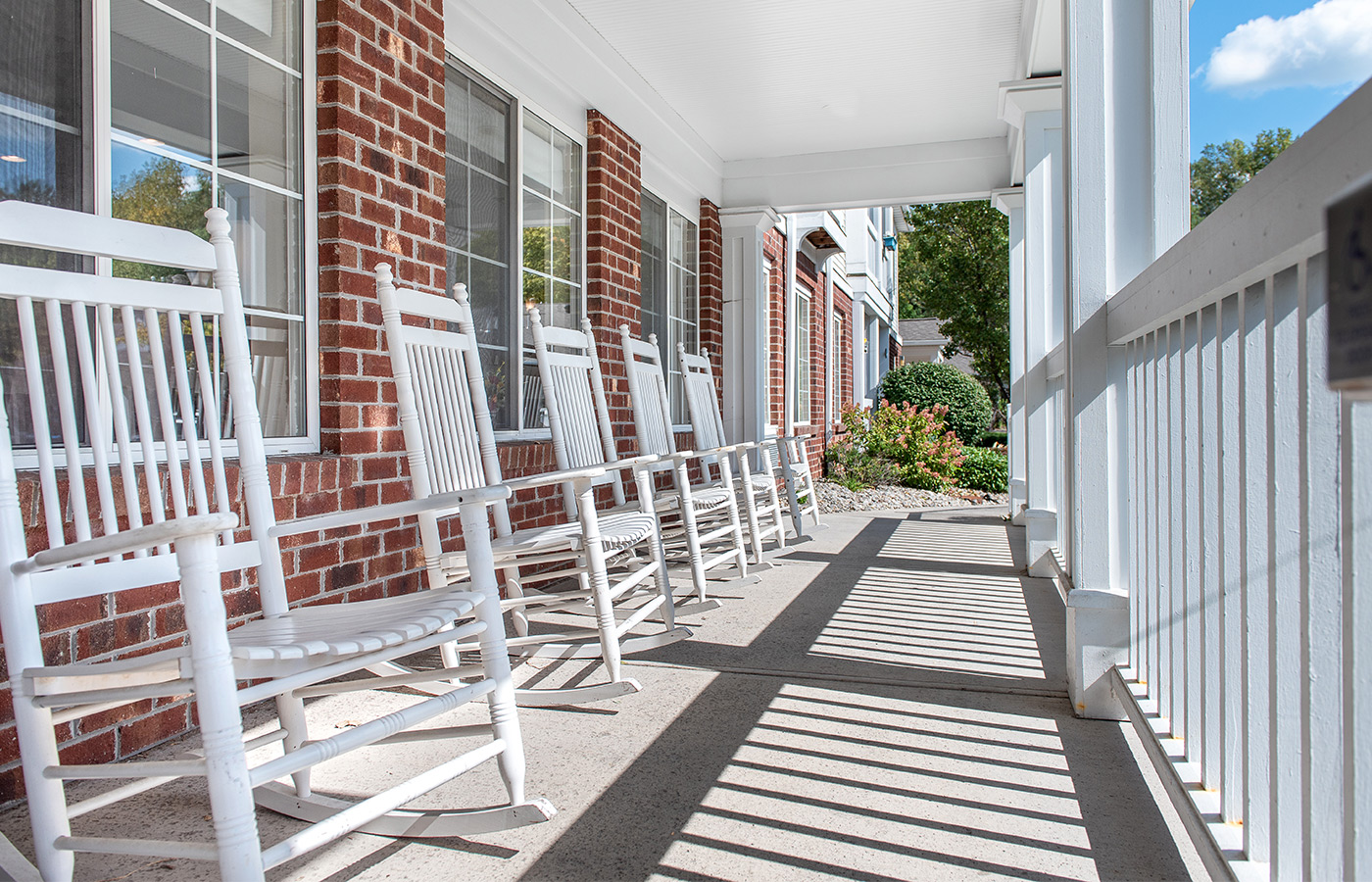 front porch with several white rocking chairs