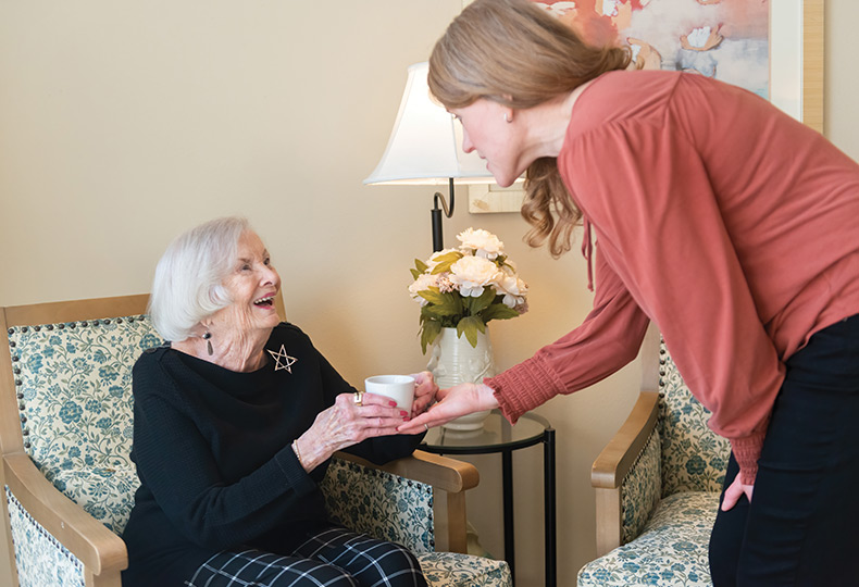 A caregiver handing coffee to a resident.